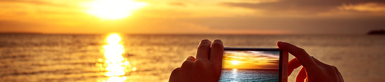 Mobiltelefon tar en bild av solnedgången.